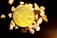 A physical representation of a Bitcoin sits among scattered small, smooth stones on a dark surface. The Bitcoin is prominently placed in the center, showcasing its intricate design and golden color.