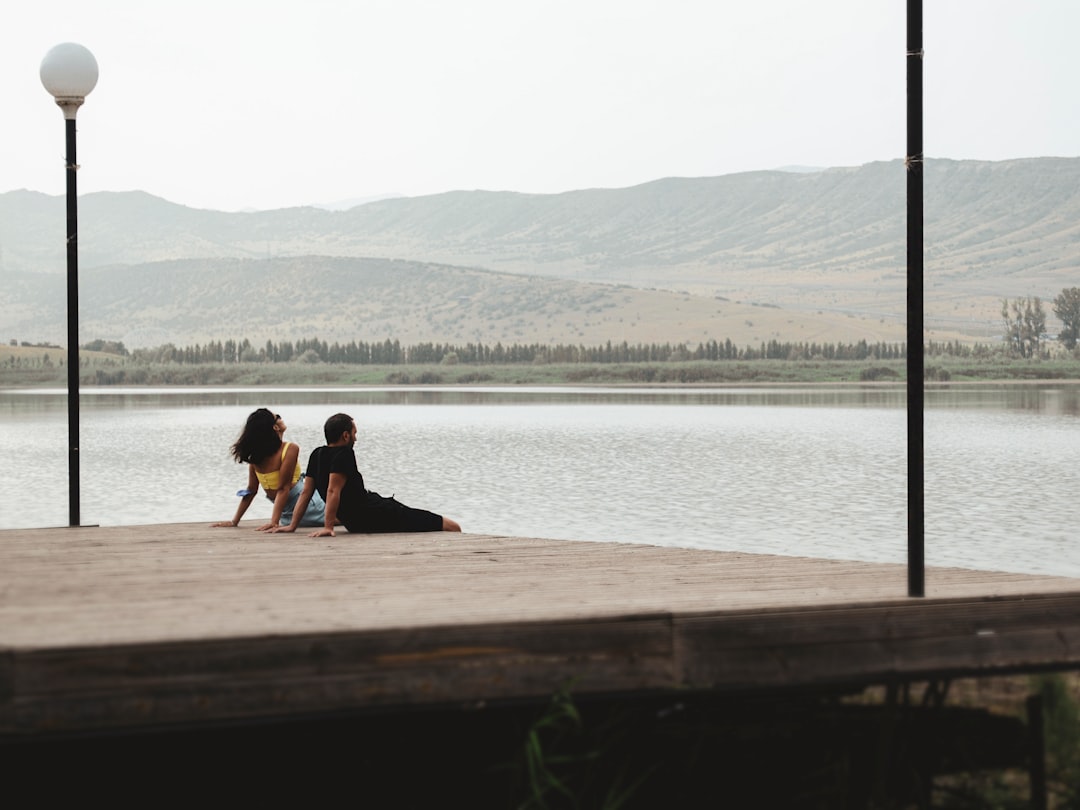 woman in black shirt sitting on brown wooden dock during daytime