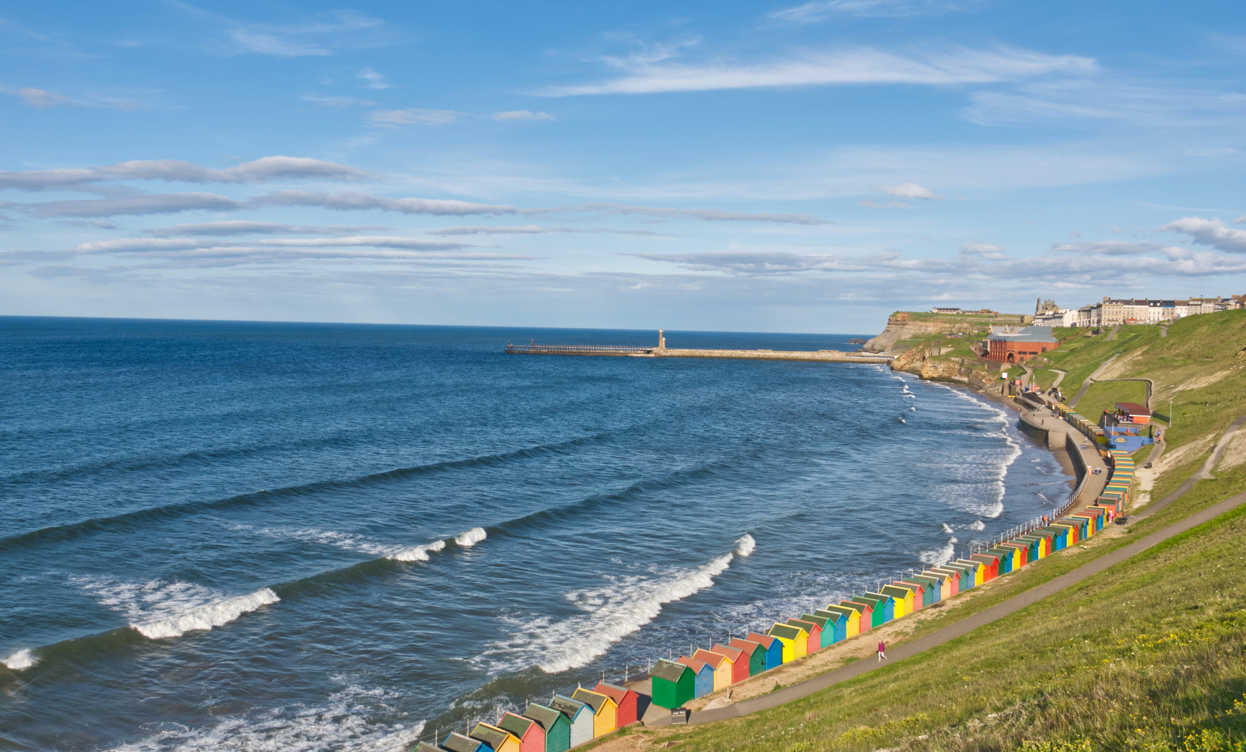 green and orange houses near sea under blue sky during daytime
