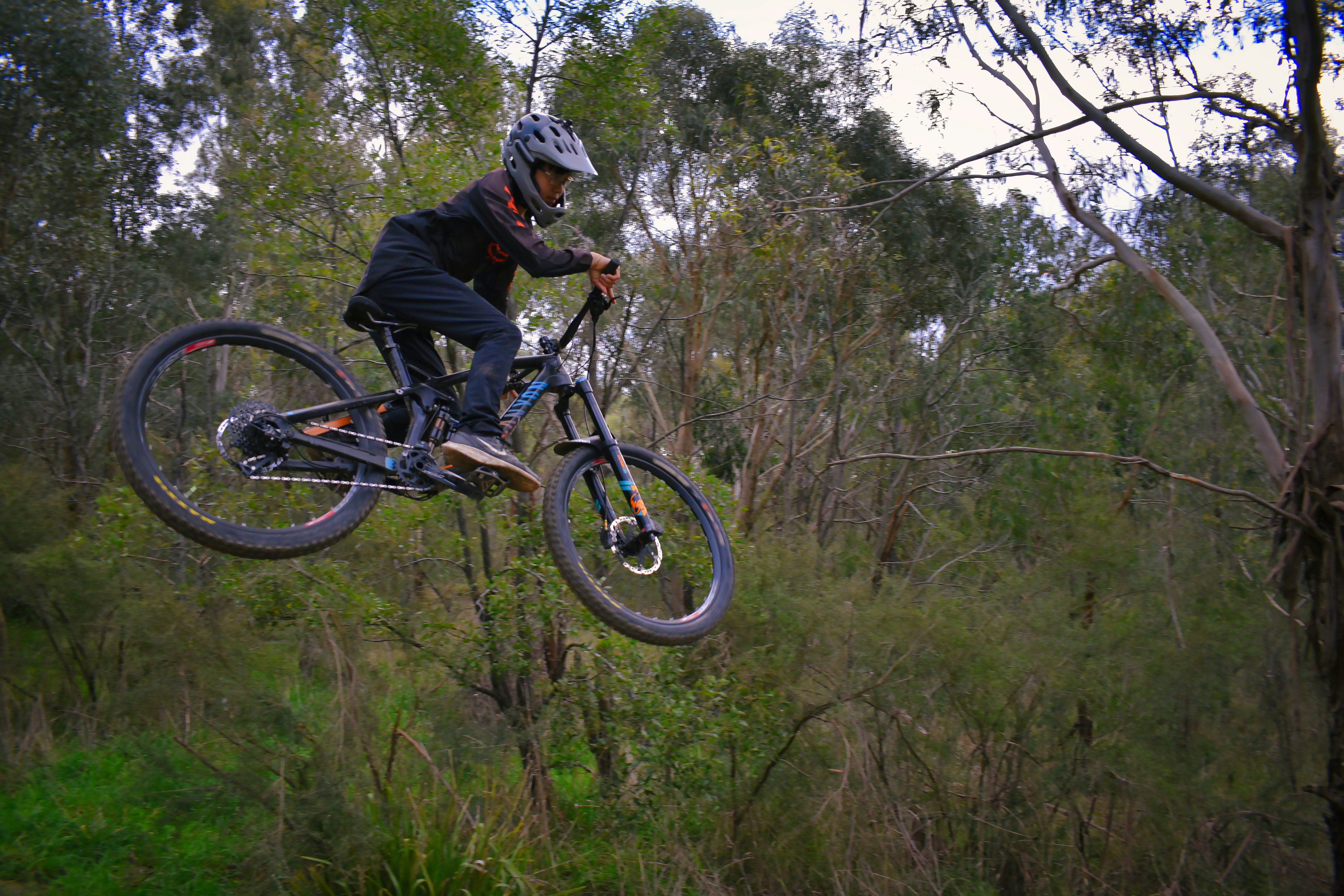 man in black jacket riding black mountain bike on forest during daytime