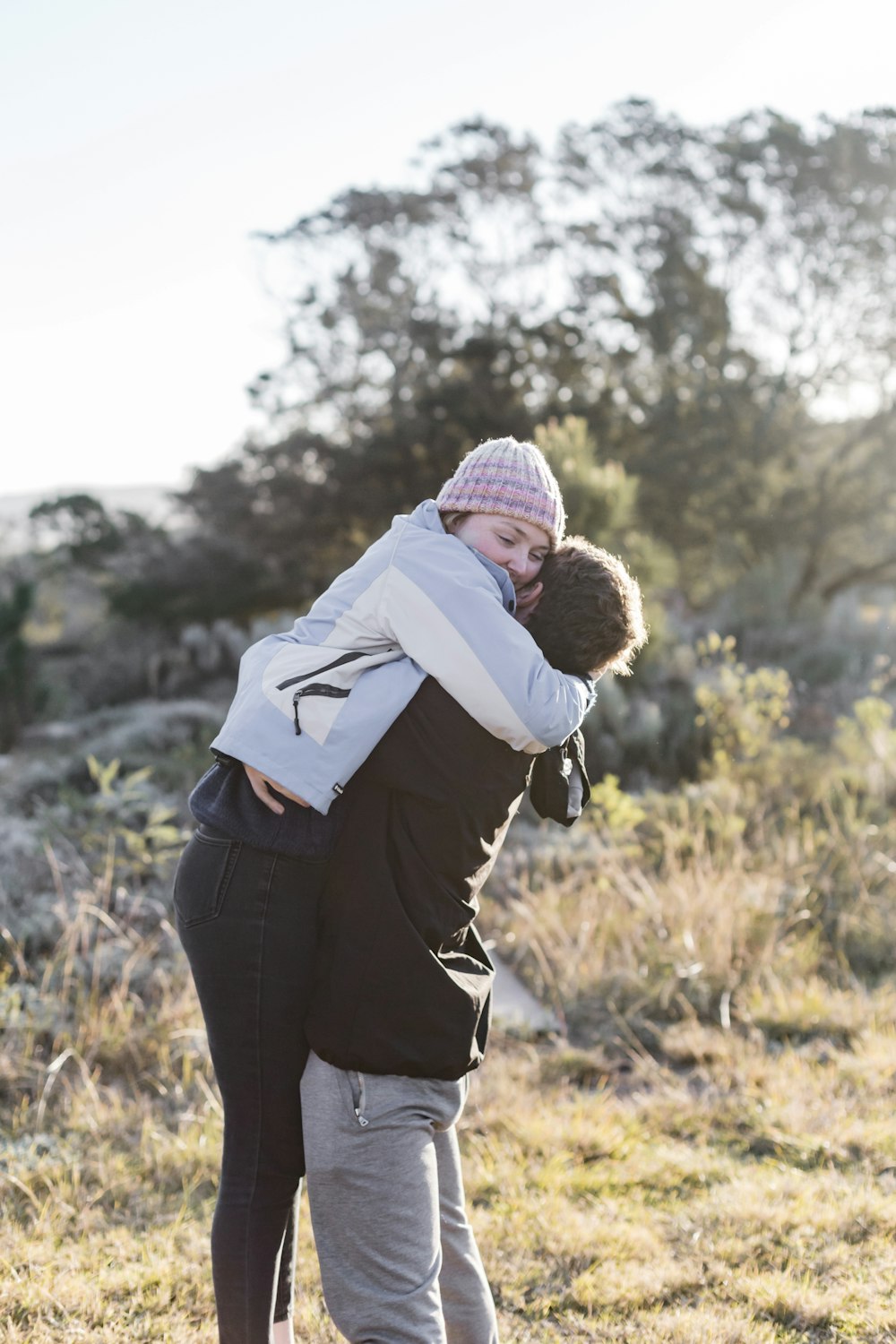 woman in black jacket carrying baby in white hoodie