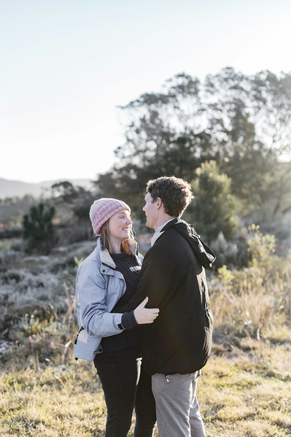 man in black suit jacket and woman in gray coat standing on green grass field during