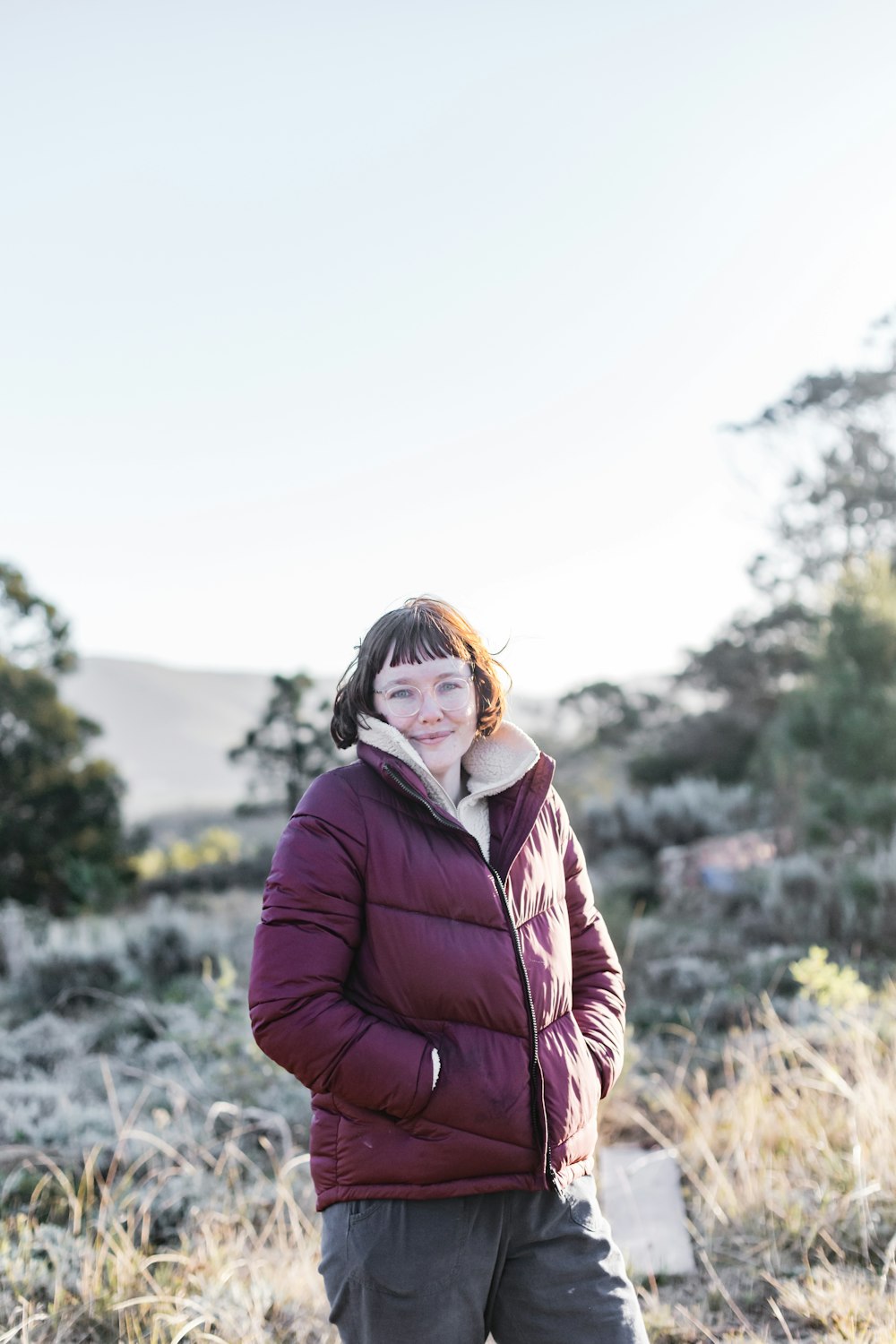 woman in maroon jacket standing on field during daytime