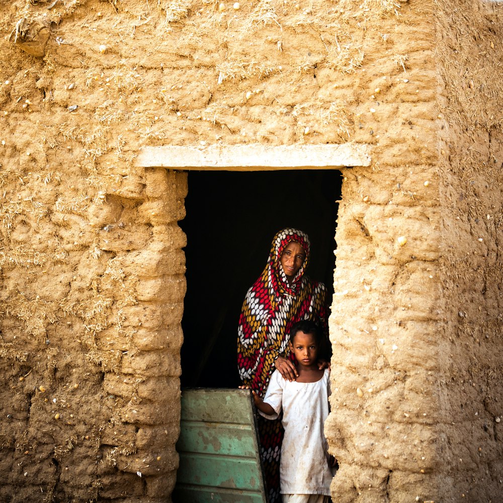 woman in white and brown dress standing in front of brown concrete wall