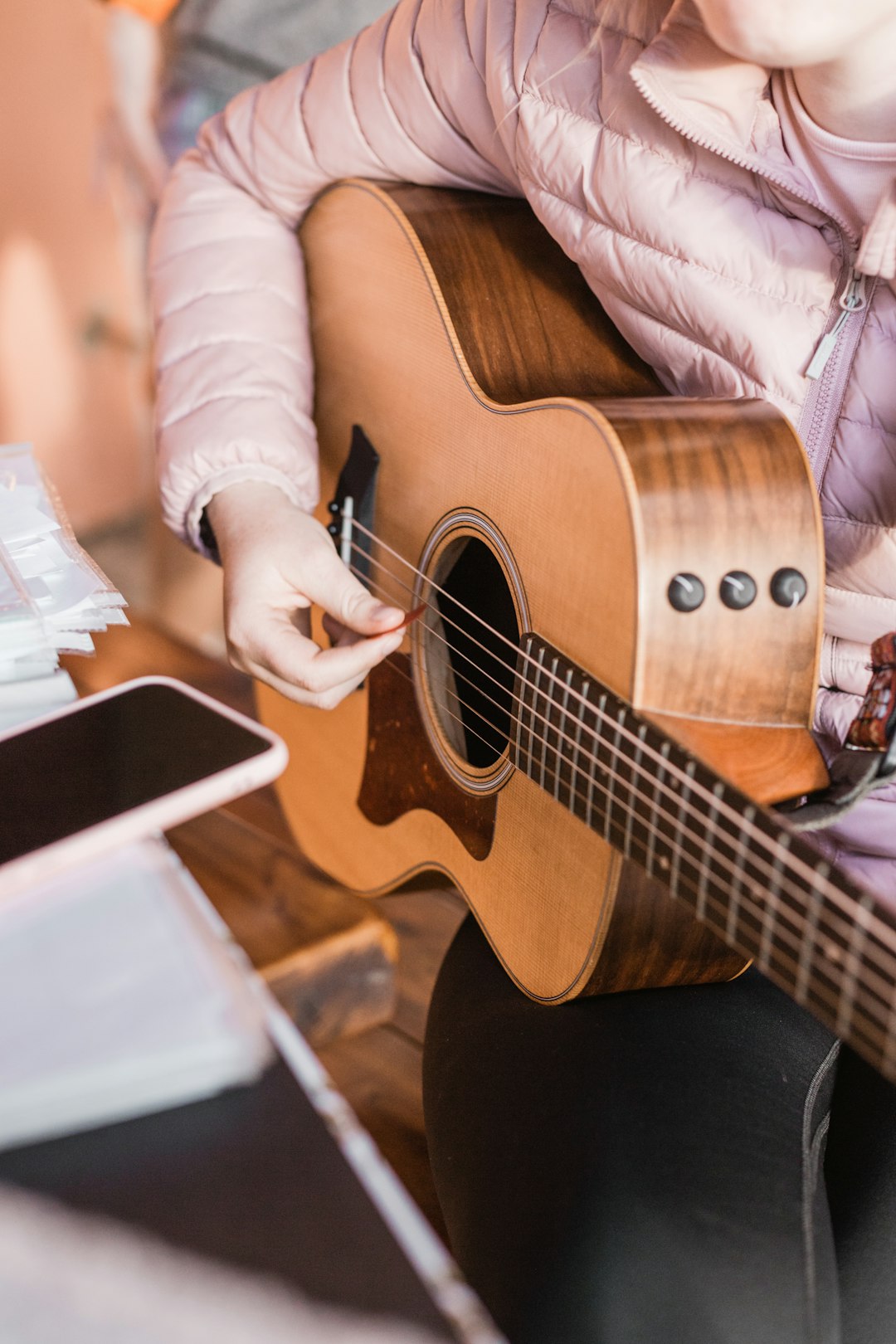 person in white long sleeve shirt playing brown acoustic guitar