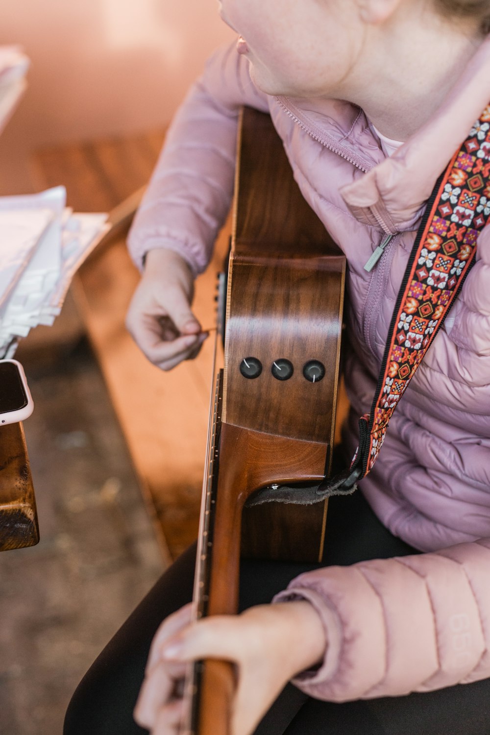 person in pink long sleeve shirt holding brown wooden guitar