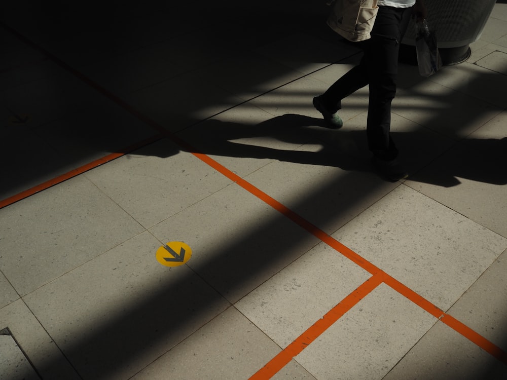 homme en veste grise marchant sur des carreaux de sol blancs et orange