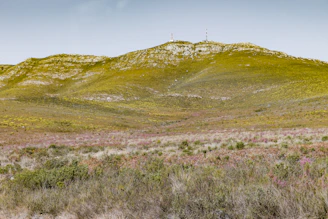 Close-up of GNSS equipment set up in a green pasture with rolling hills in the background.