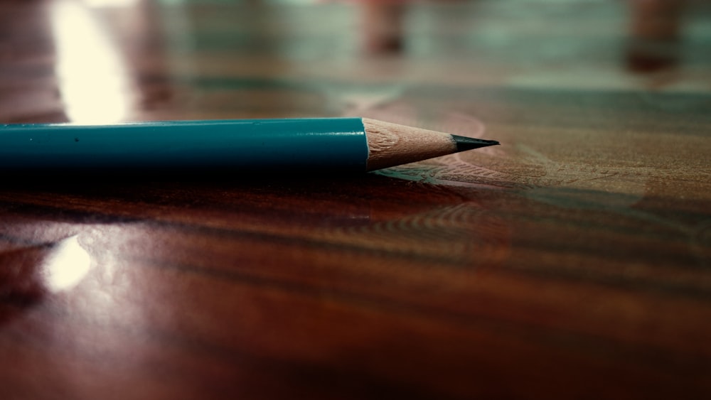 caneta azul e cinza na mesa de madeira marrom