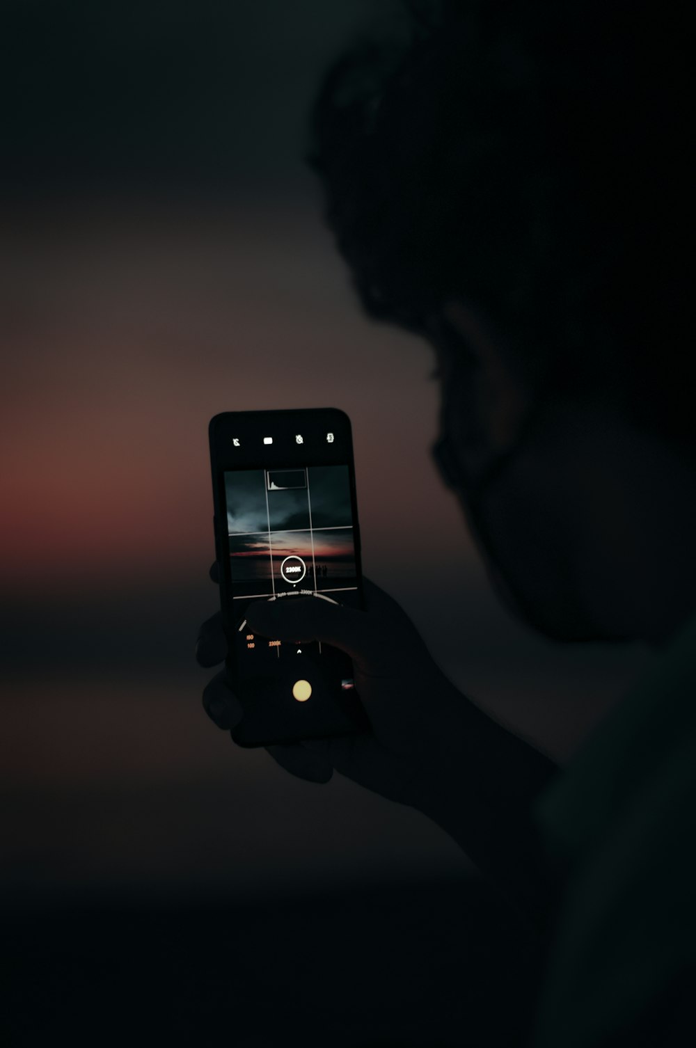 person holding iphone taking photo of sun