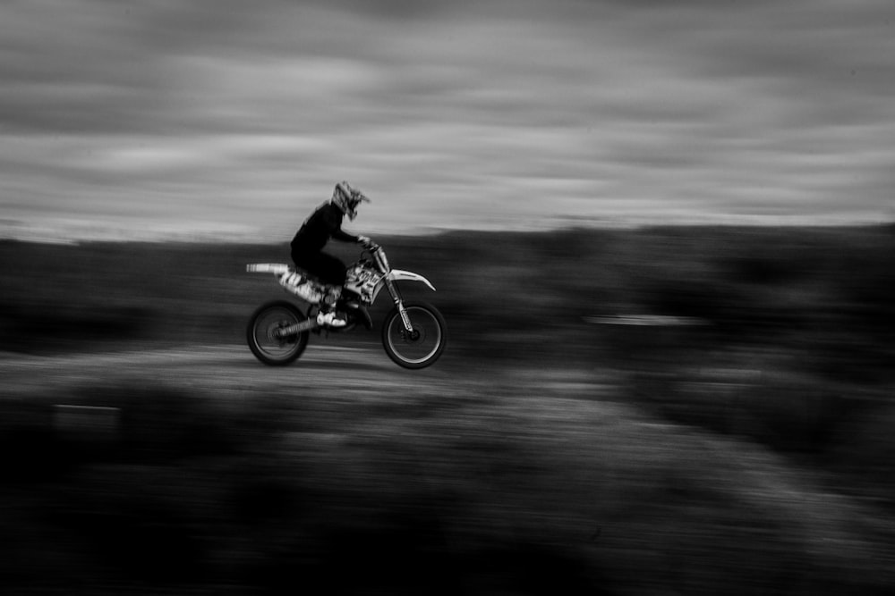 grayscale photo of man riding motocross dirt bike