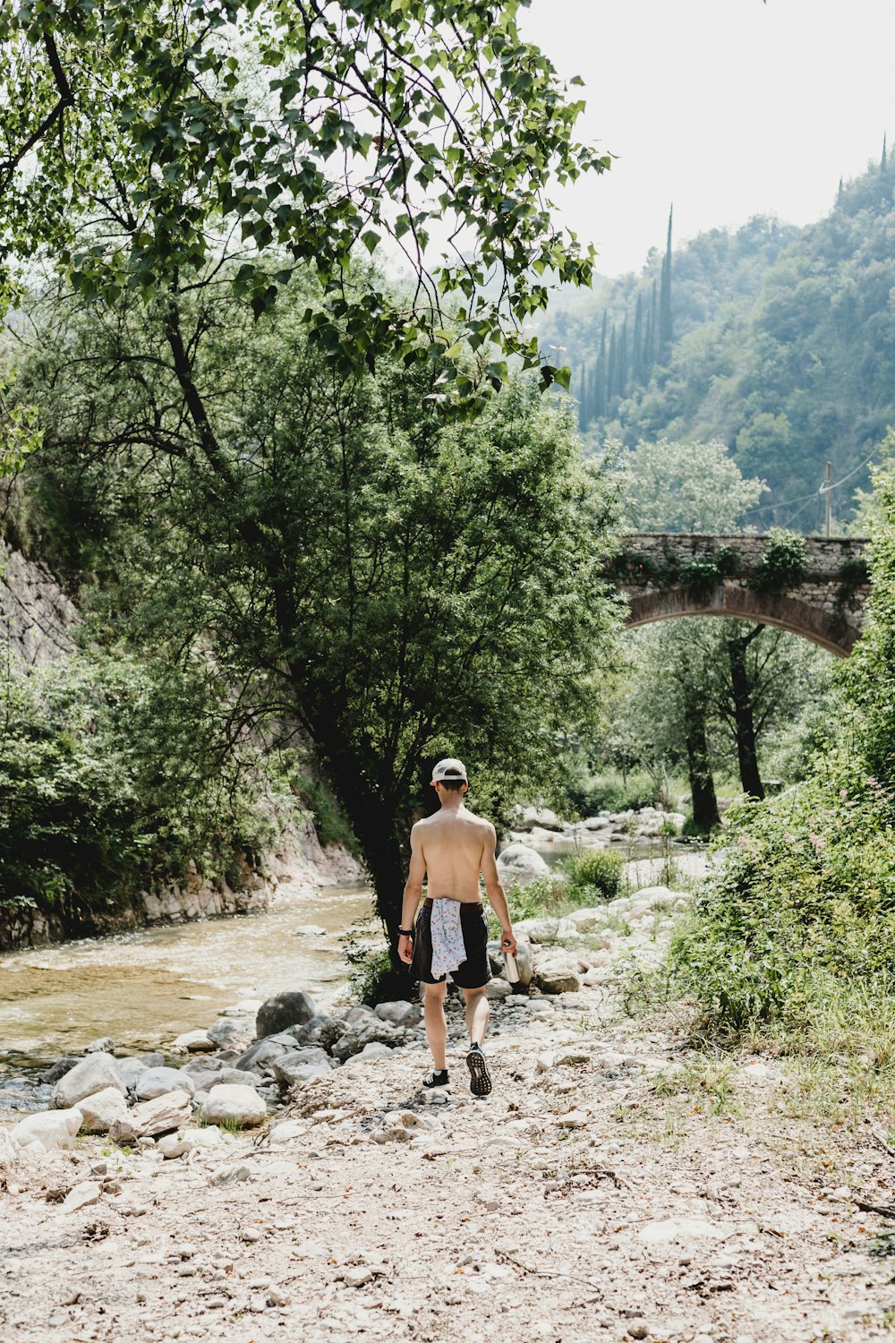 Hombre en pantalones cortos marrones de pie en el río rocoso durante el día