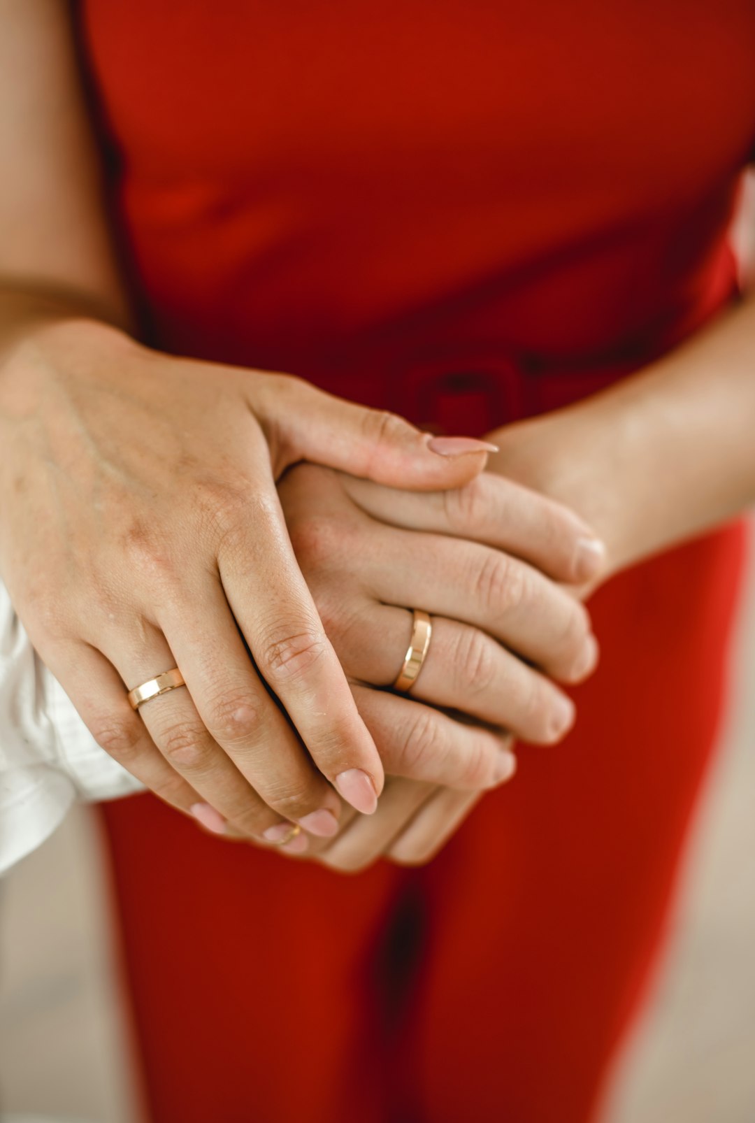 woman in red dress holding mans hand