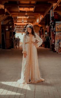 woman in white long sleeve dress standing on gray concrete floor during daytime