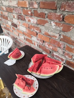 Bright red watermelon slices arranged on a wooden table with green leaves around.