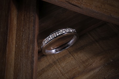 silver diamond ring on brown wooden table