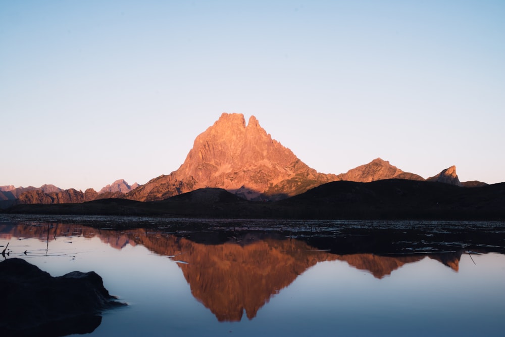 brown mountain near body of water during daytime