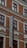 A multi-story brick building with large windows framed by white moldings. The prominently featured vertical sign reads 'Hollandia'. The structure displays a classic architectural style with red brickwork and decorative elements.