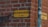 A yellow street sign with black letters is mounted on a red brick wall at a corner. The text reads 'BÄSTEBRORSGRÄND KV. THOR'. Next to the street sign, there is a pole with a sticker that has some graphic and text on it.