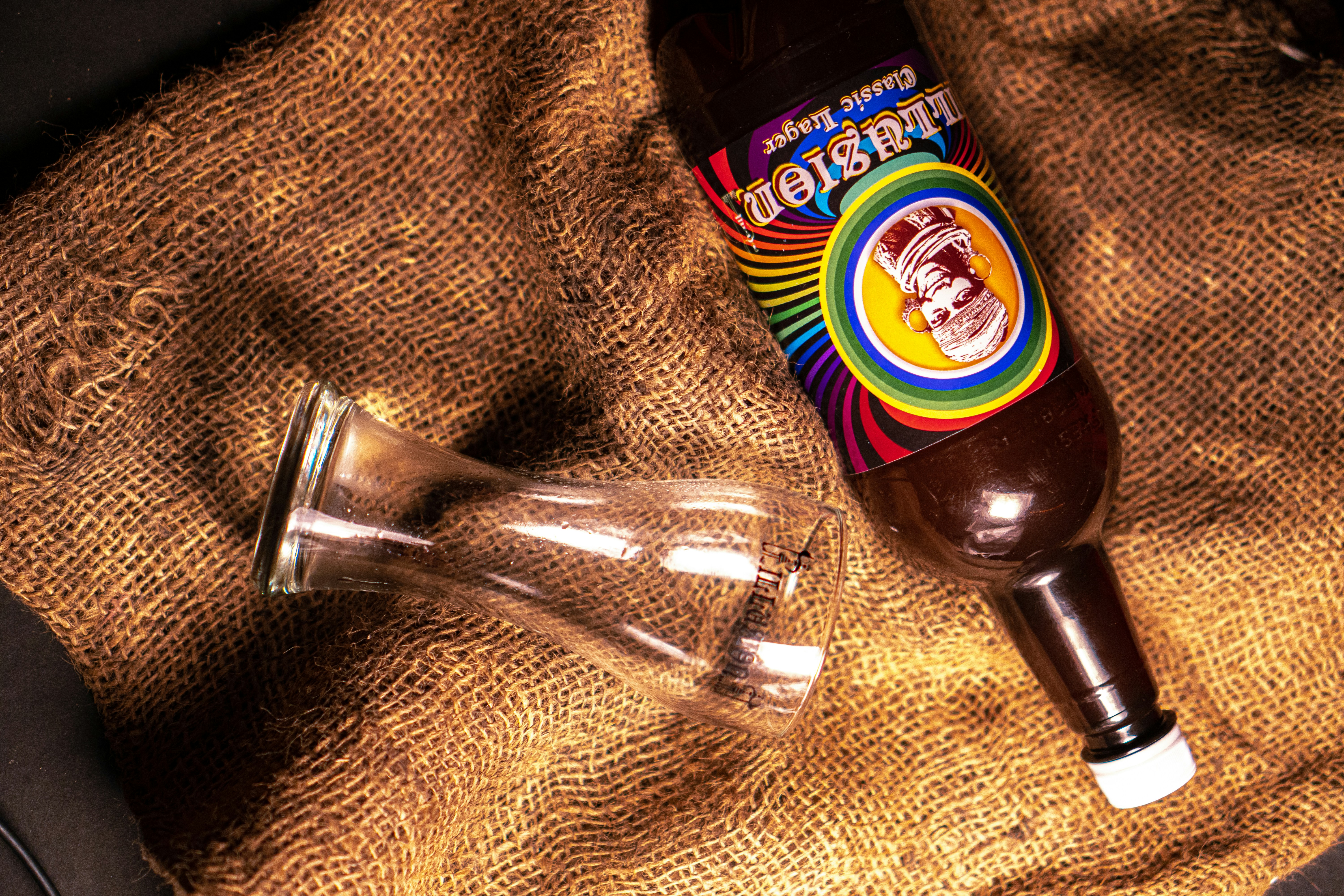 blue and white labeled bottle beside clear drinking glass