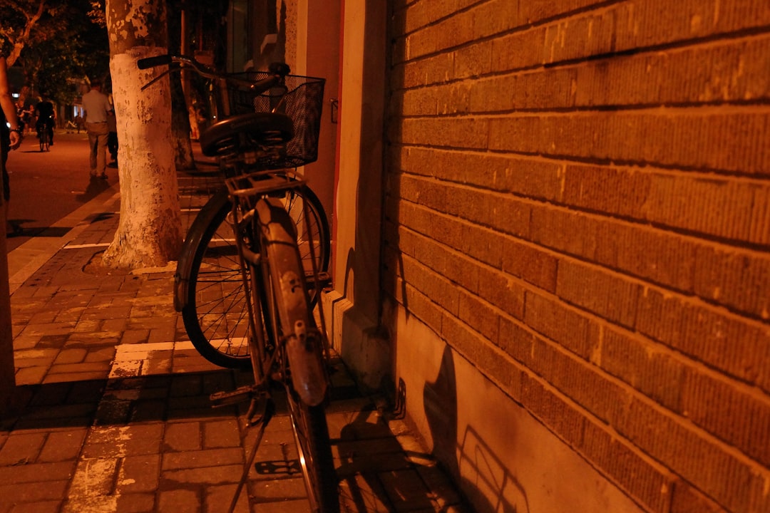 black bicycle leaning on brown brick wall