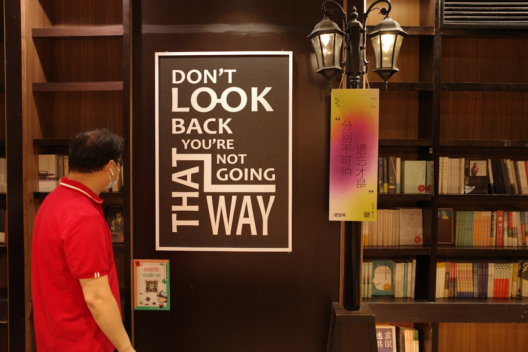 man in red t-shirt standing near brown wooden door