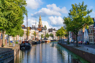 boat on river near green trees and buildings during daytime