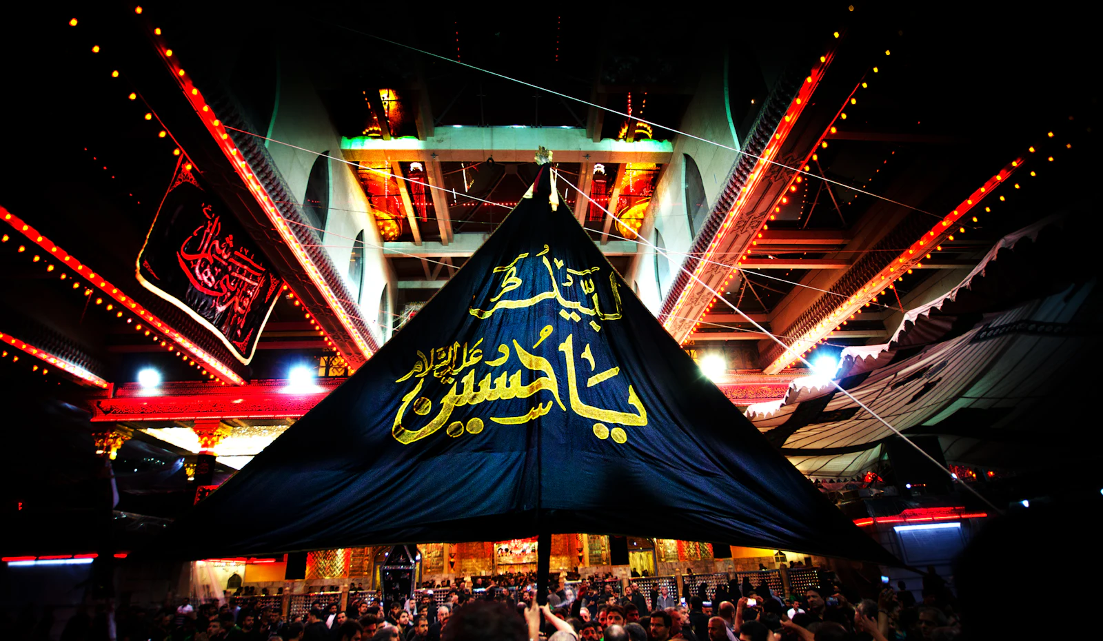 Night lights and banners above pilgrims at the shrine