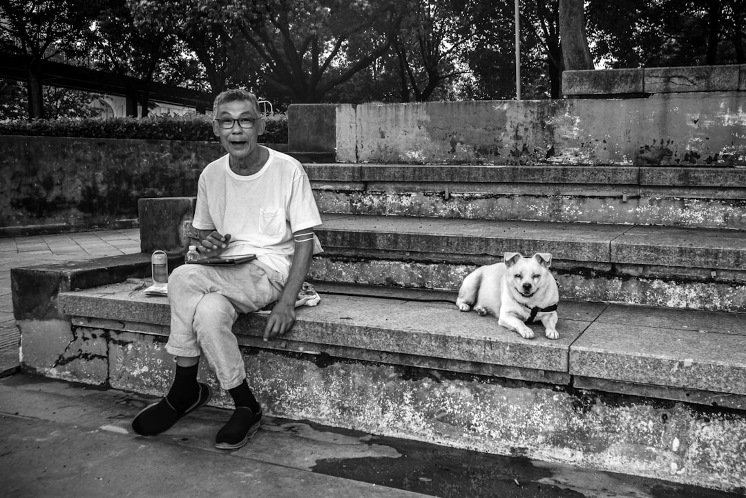 man in white crew neck t-shirt sitting on concrete bench beside white short coated dog