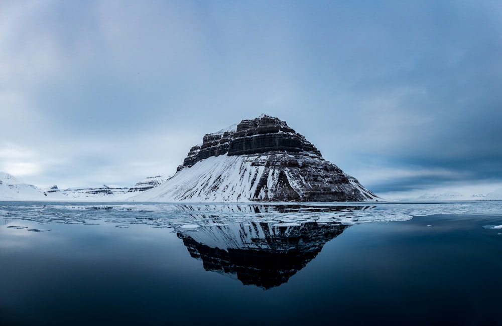 snow covered mountain near body of water