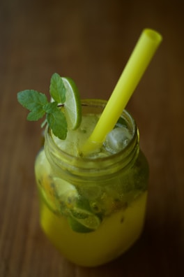 Refreshing lemonade in a mason jar with a slice of lime and mint leaves.
