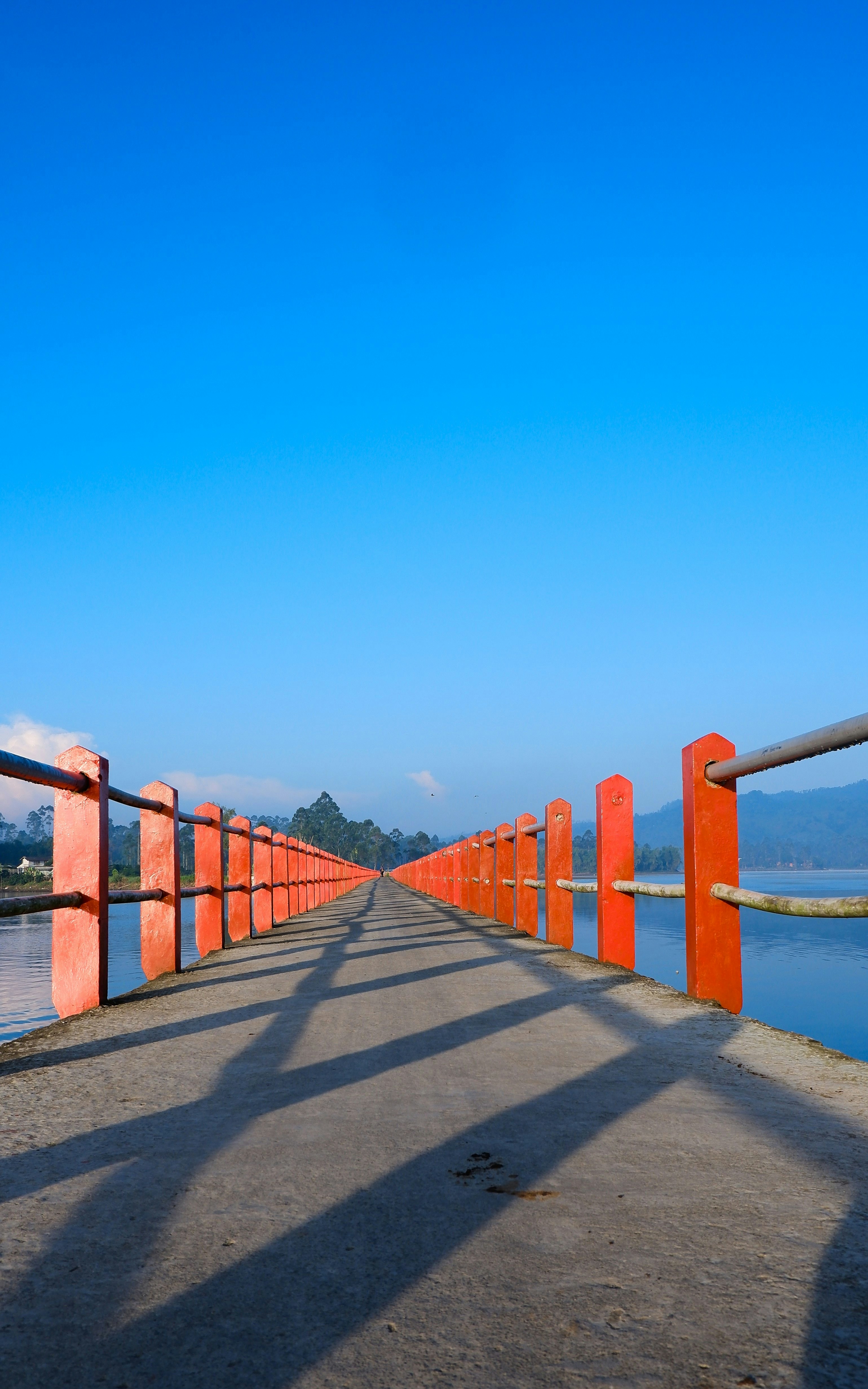 jembatan kayu coklat di atas laut biru di bawah langit biru di siang hari