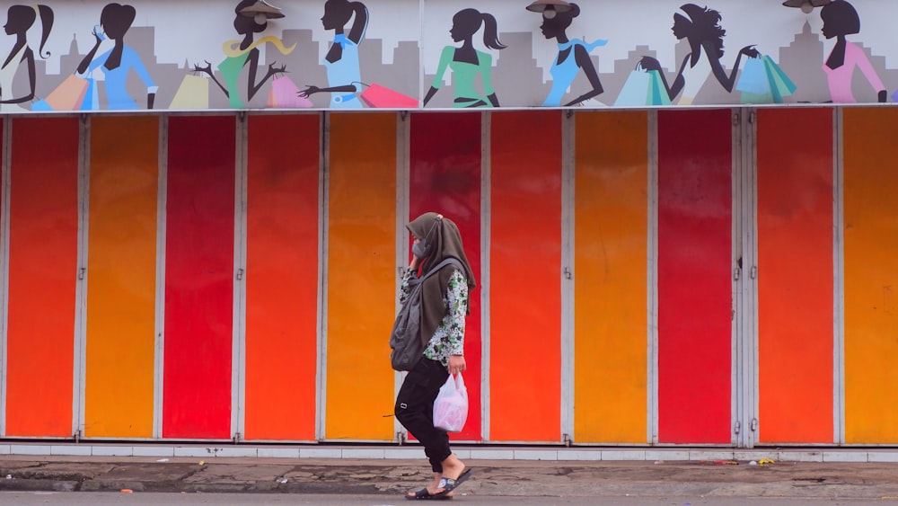 woman in white and black jacket standing near wall with minnie mouse and mickey mouse wall