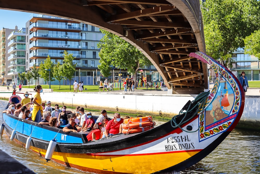 people riding on red and blue boat during daytime