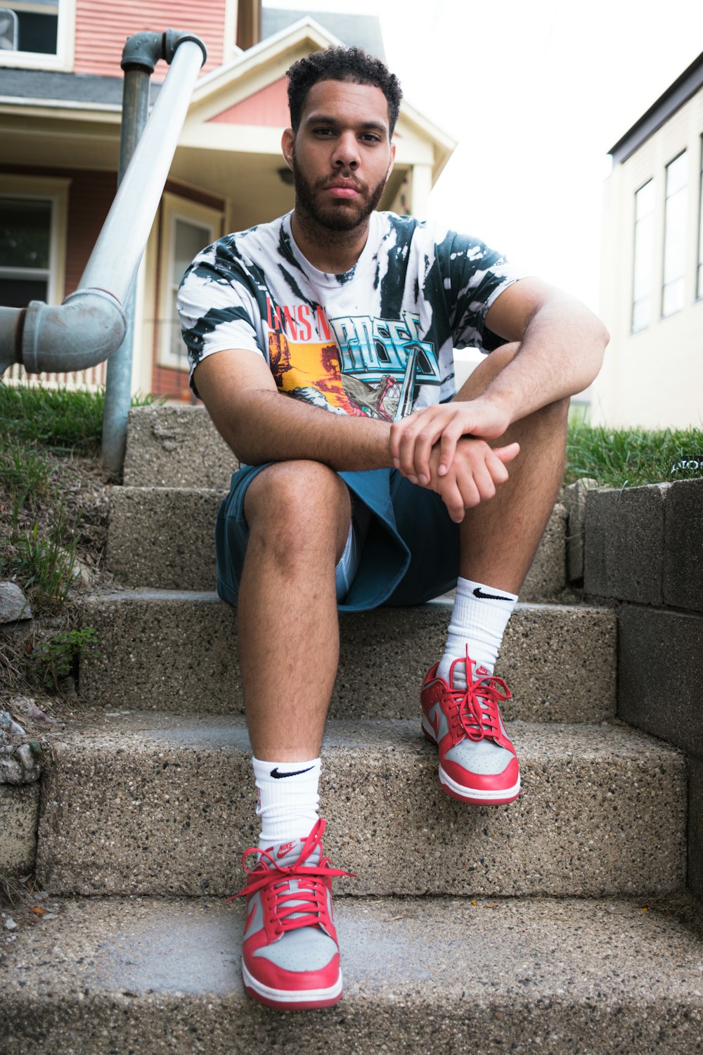 woman in white and red crew neck t-shirt sitting on concrete stairs