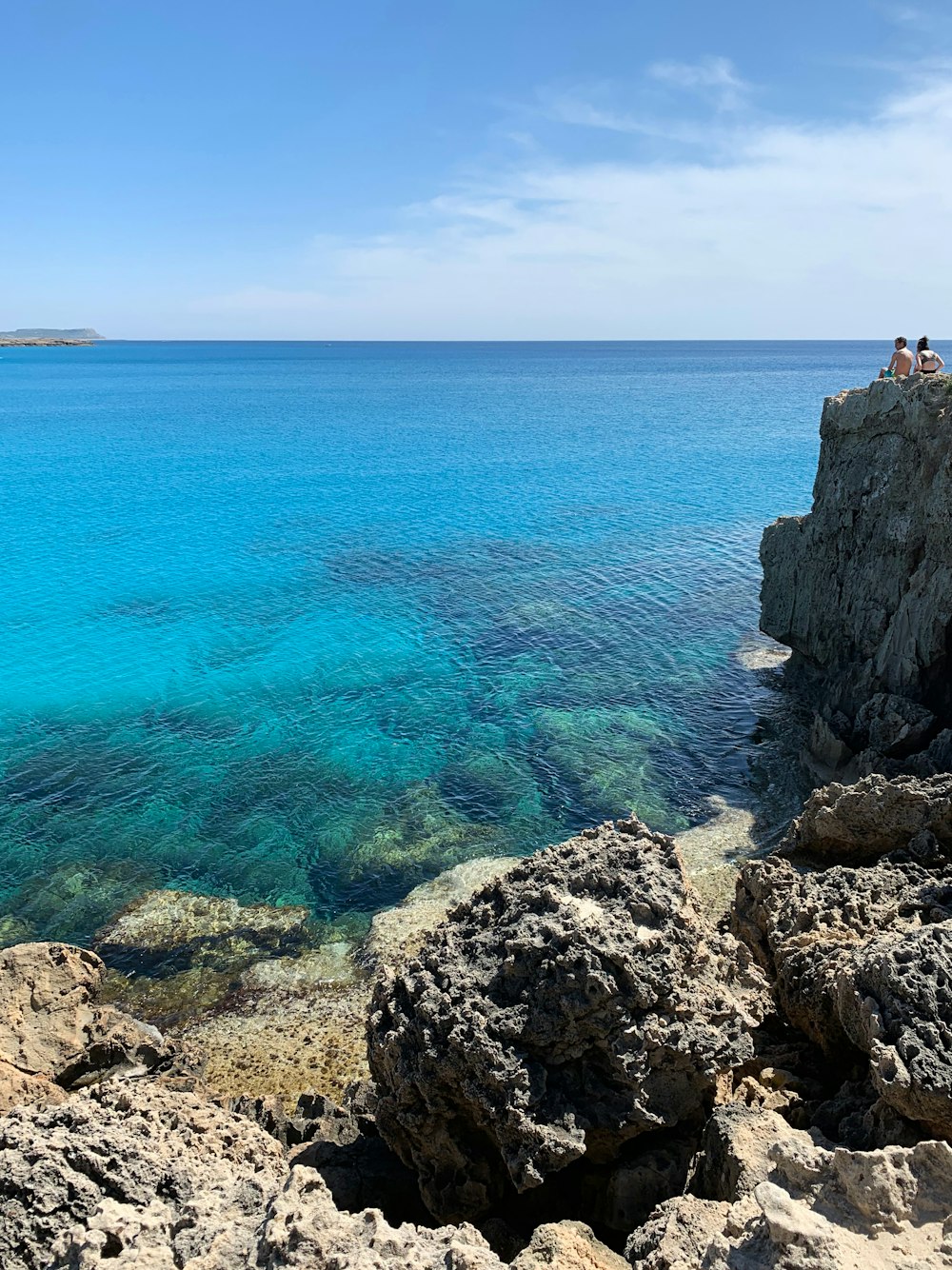 person standing on rock formation near body of water during daytime