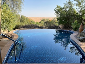 A modern infinity pool with clean lines and a serene desert backdrop at sunset.