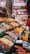 An organized display of various colorful spices and herbs in a vibrant marketplace. The spices are neatly arranged in rows, each with a distinctive color and texture, creating a visually appealing pattern. A large banner with 'Hazer Baba' is visible in the background, emphasizing a focus on quality.