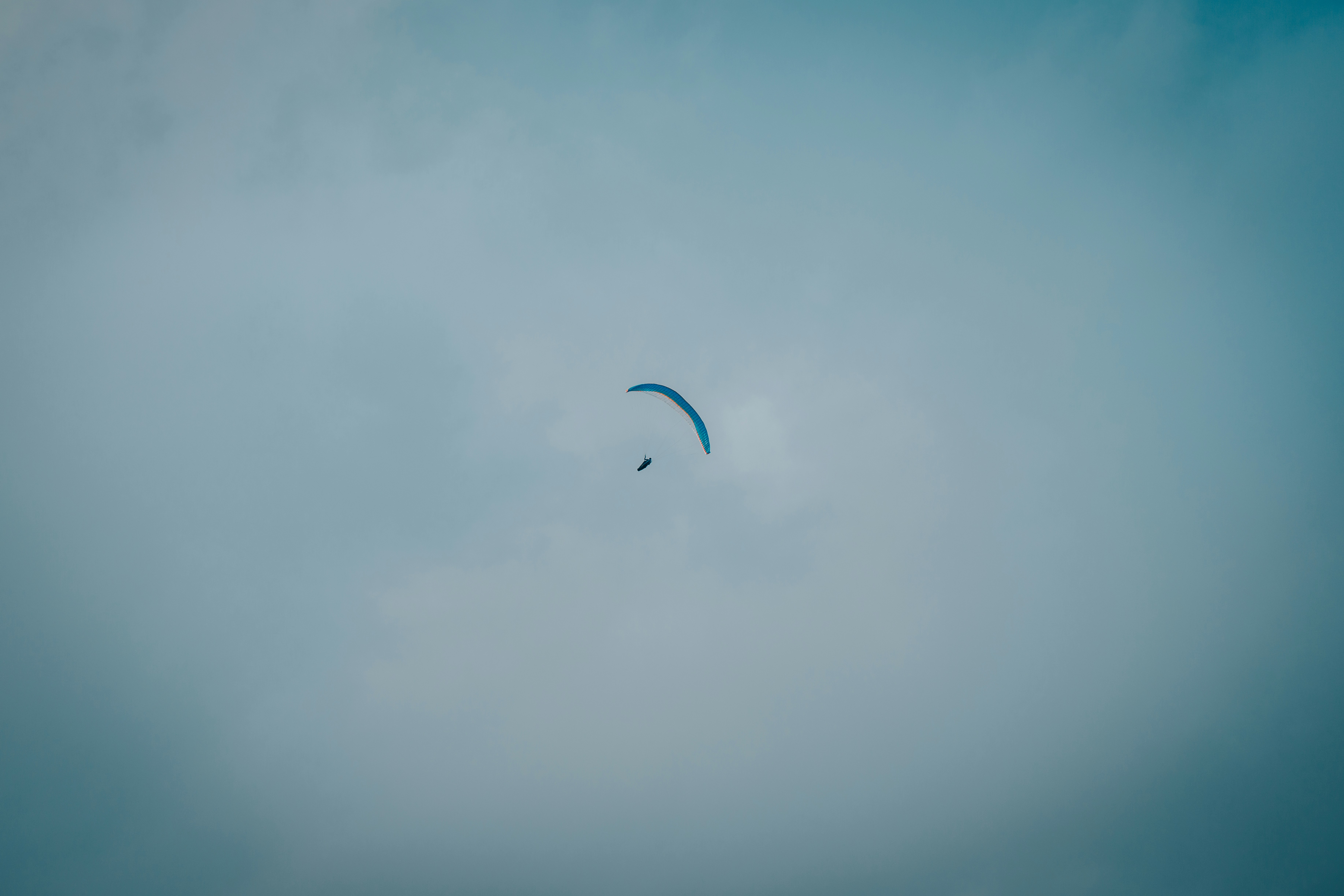 person in white shirt with parachute in the sky