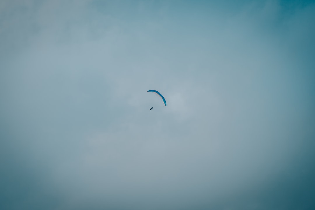 person in white shirt with parachute in the sky