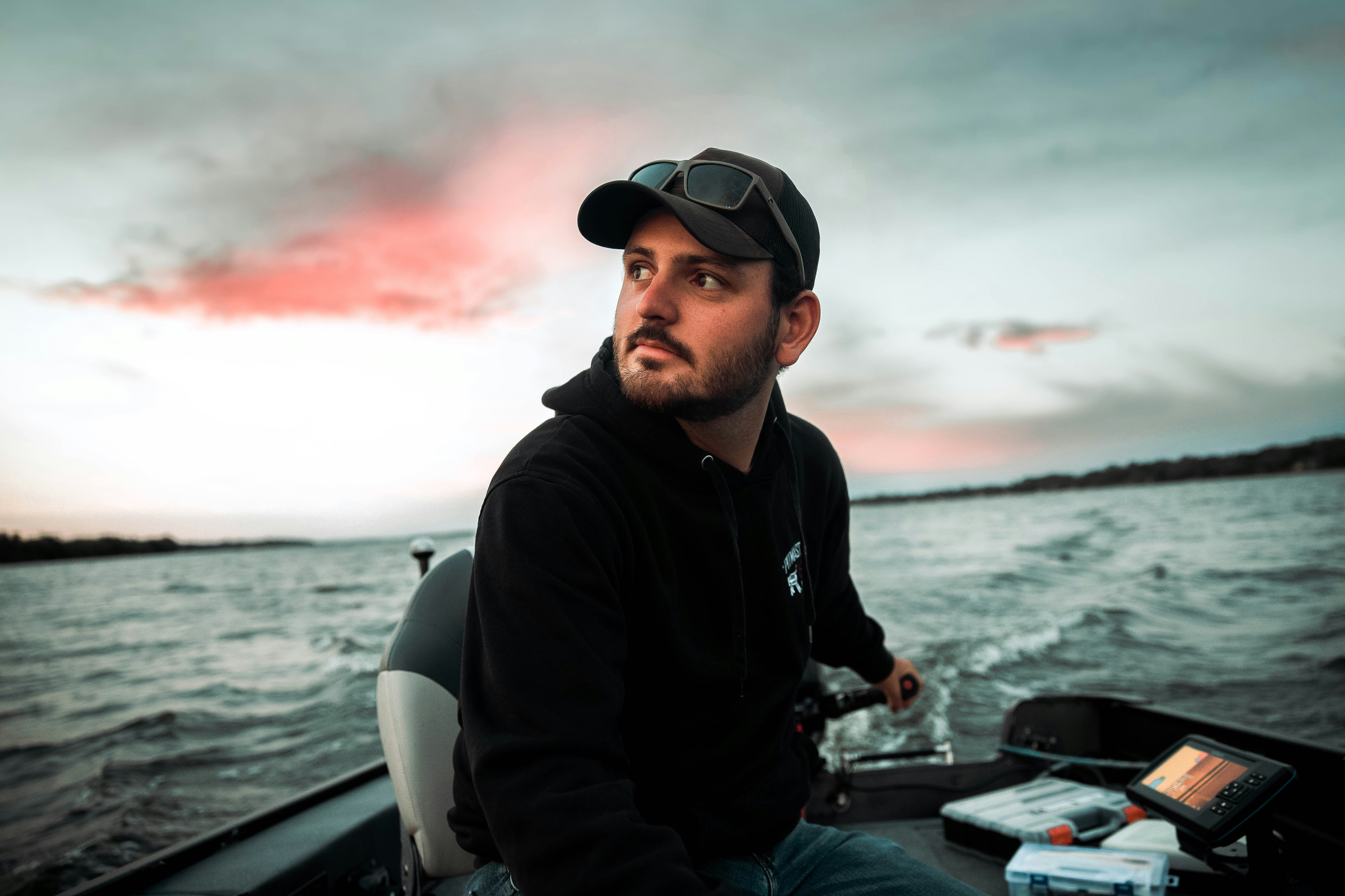 Mann in schwarzer Jacke und schwarzer Mütze sitzt tagsüber auf schwarz-weißem Motorrad