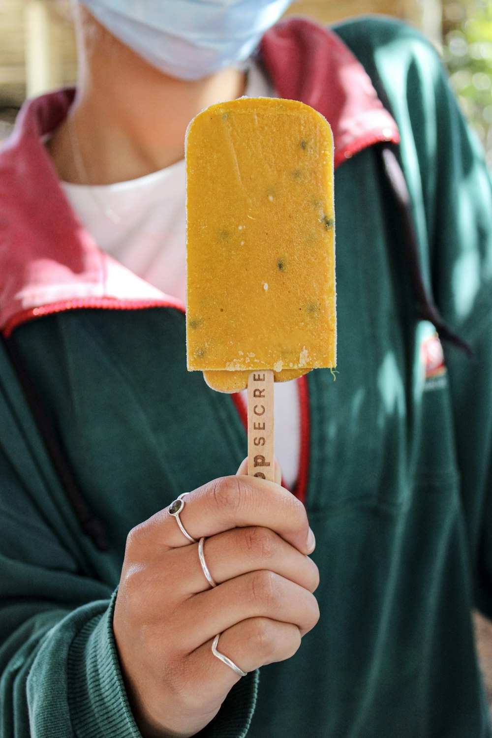 Persona sosteniendo una paleta helada amarilla