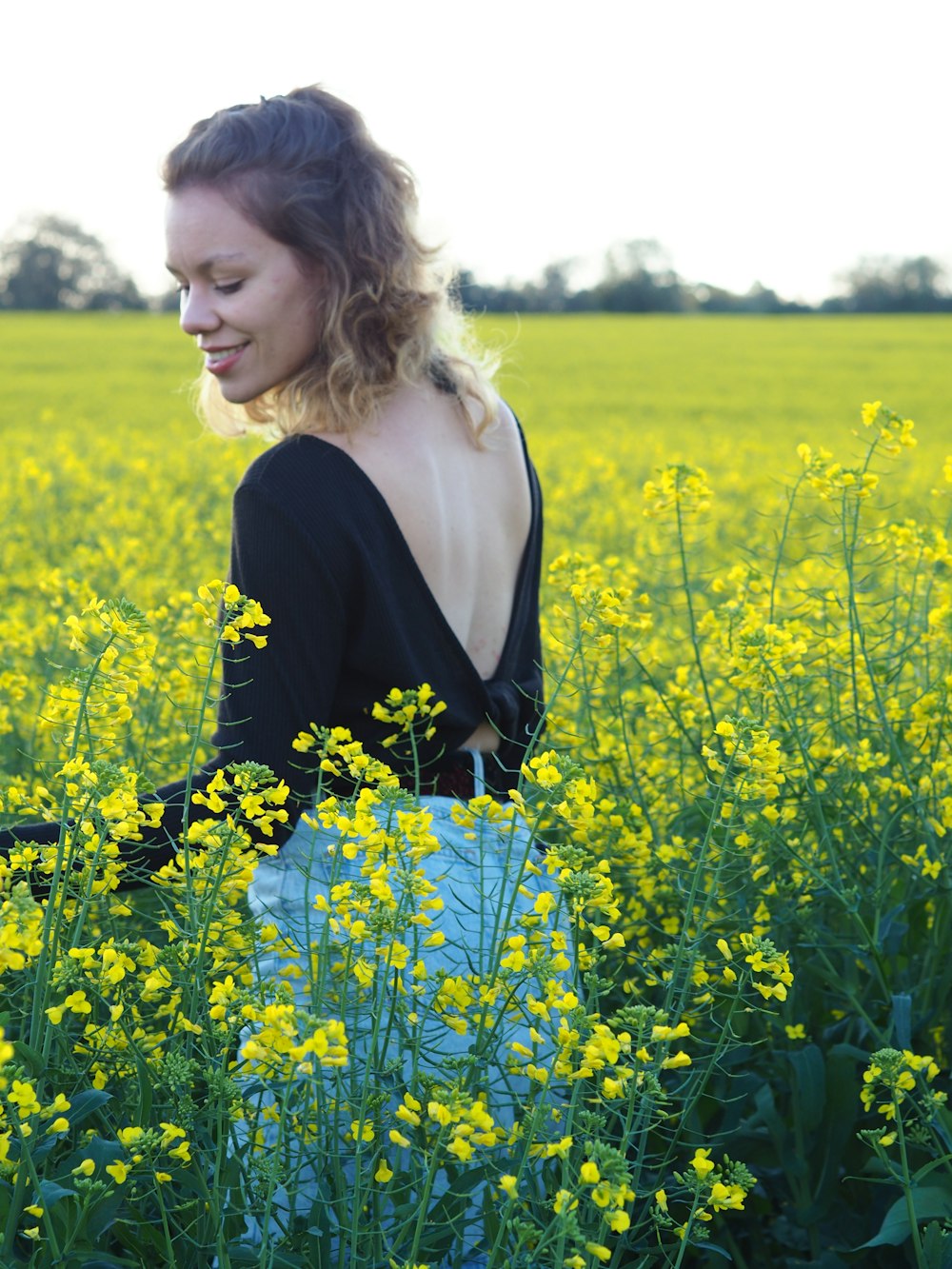 woman in black long sleeve shirt standing on yellow flower field during daytime