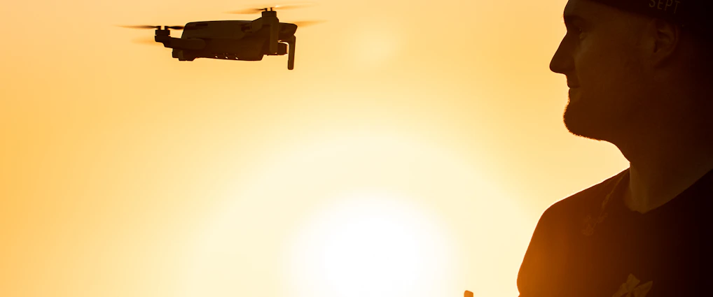 silhouette of man holding drone