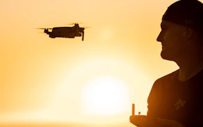 silhouette of man holding drone