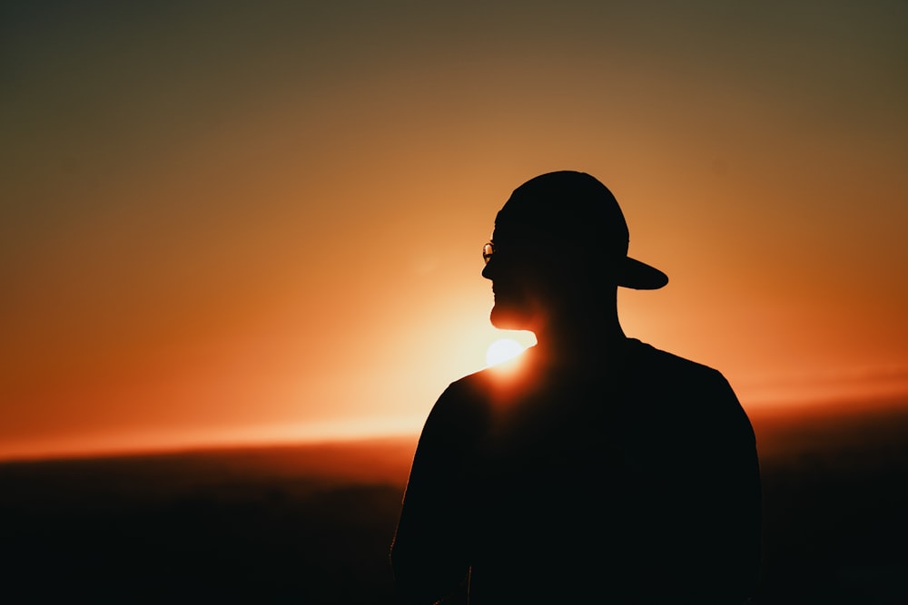 silhouette of man wearing hat during sunset