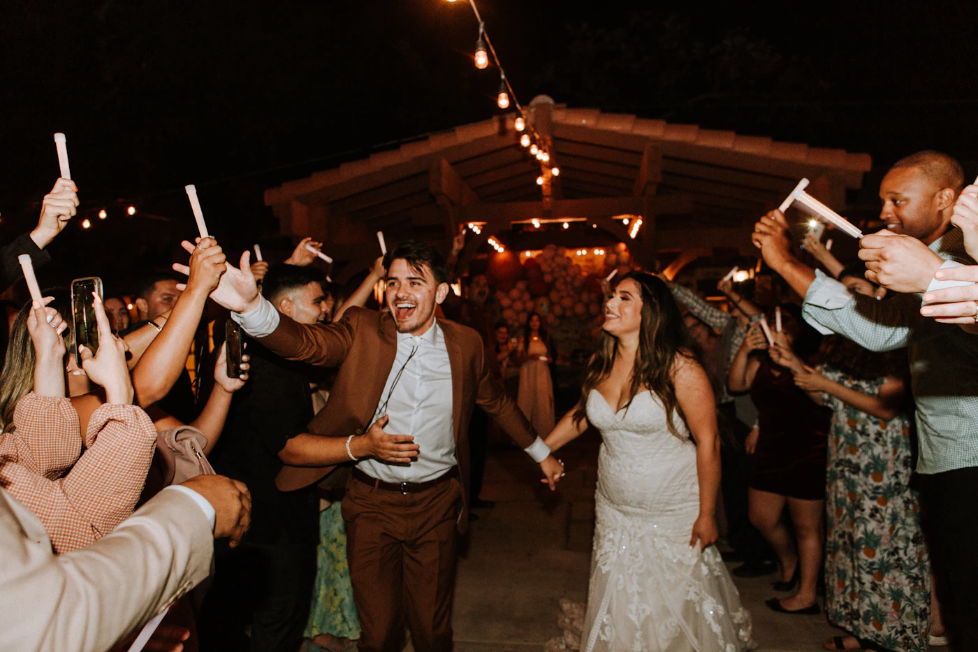 Wedding guests dancing late at night beneath strings of warm light