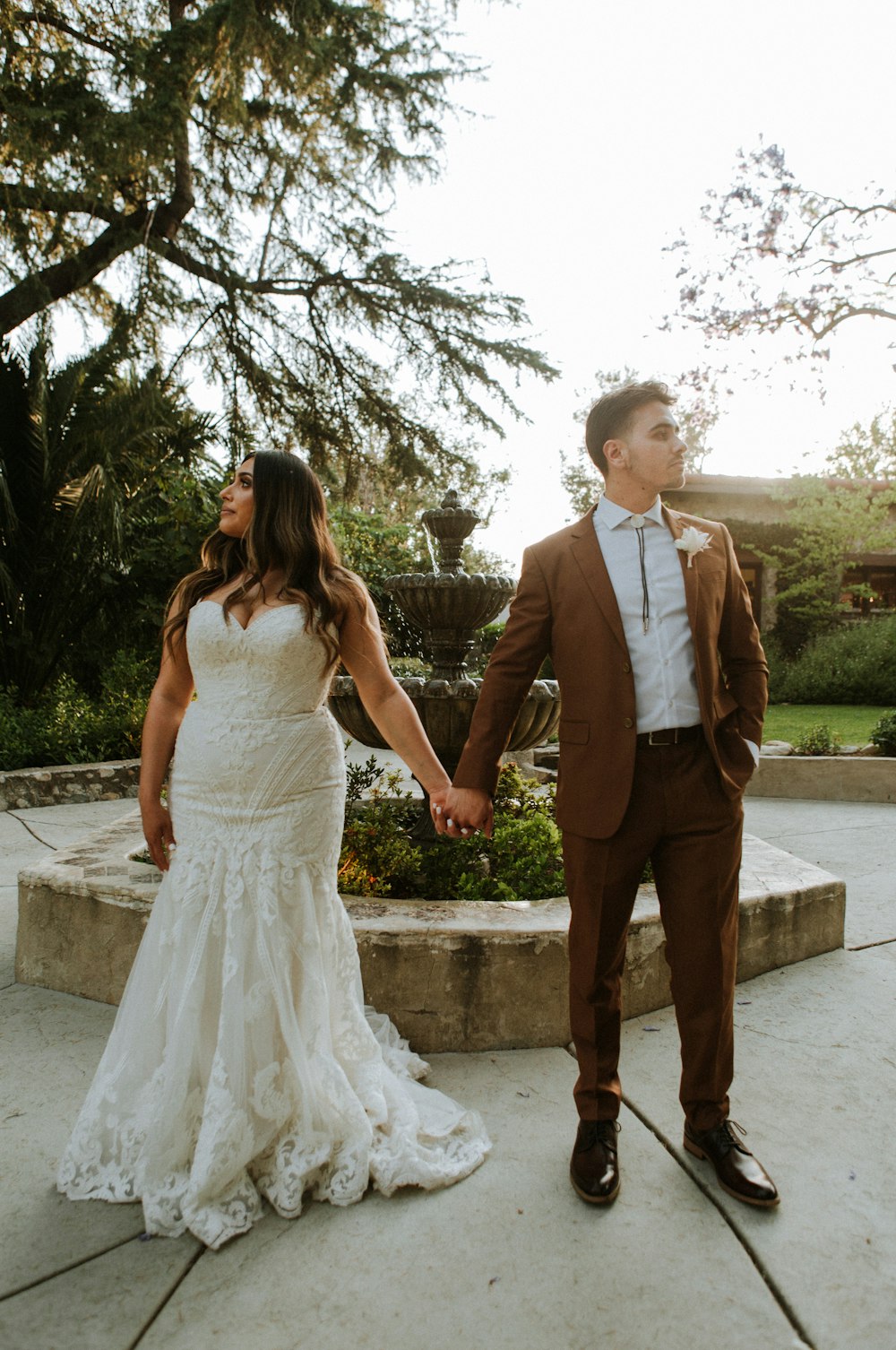 man in brown suit and woman in white dress walking on sidewalk during daytime