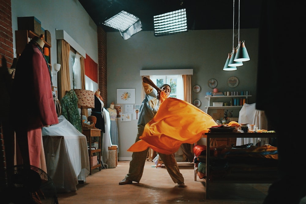 man in orange robe standing near brown wooden table