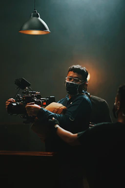 Portrait of a focused videographer working with a camera in a dimly lit studio, reflecting a cinematic mood.